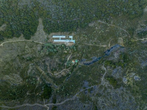 Vista aérea de un albergue de montaña rodeado de matorrales de altura y senderos