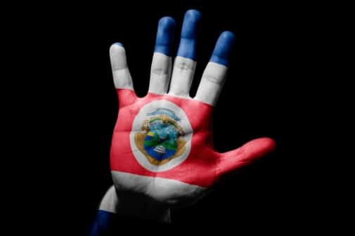 Mano levantada pintada con la bandera y el escudo de Costa Rica sobre fondo negro