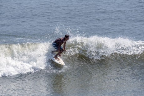Surfista deslizándose sobre una ola que rompe con espuma blanca