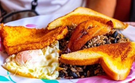 Plato de desayuno con gallo pinto, huevo frito, plátano maduro frito y pan tostado